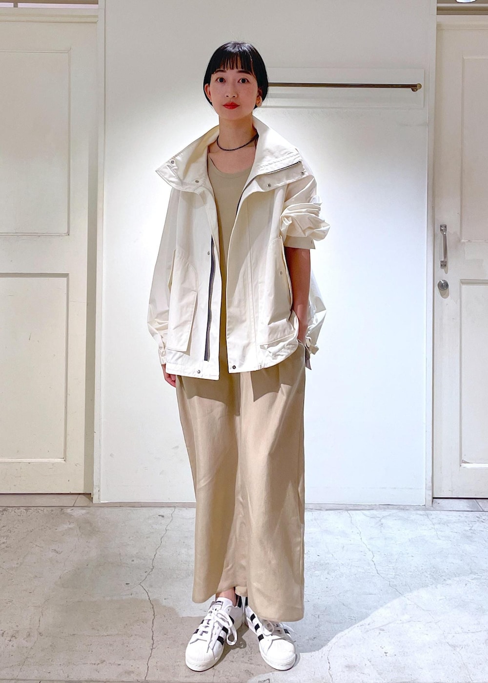 ベージュ系のワンピース、ホワイト系のブルゾン、ホワイト系のスニーカーを着用したレディースの冬コーディネートの5枚目の写真