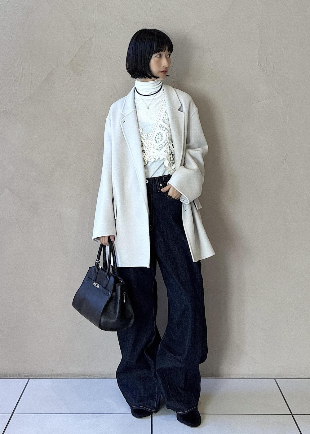 ホワイト系のその他アウター、ホワイト系のチェスターコート、ブラック系のハンドバッグを着用したレディースの秋コーディネートの2枚目の写真