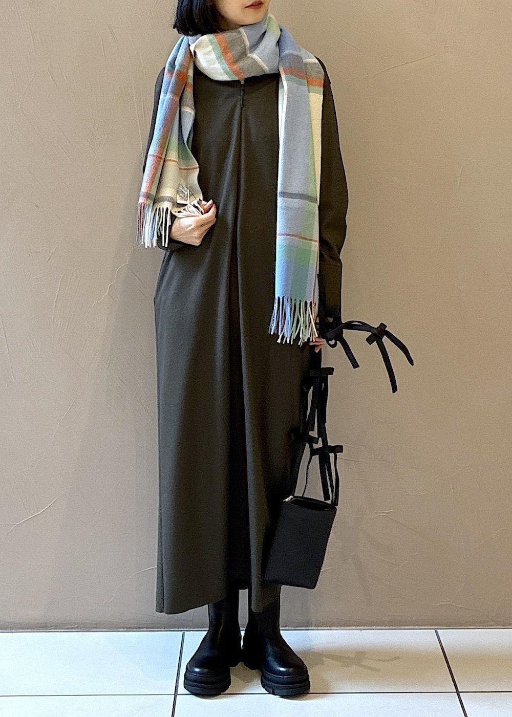 ブラック系のブーツ、グリーン系のワンピース、ホワイト系のニット/セーターを着用したレディースの冬コーディネートの5枚目の写真