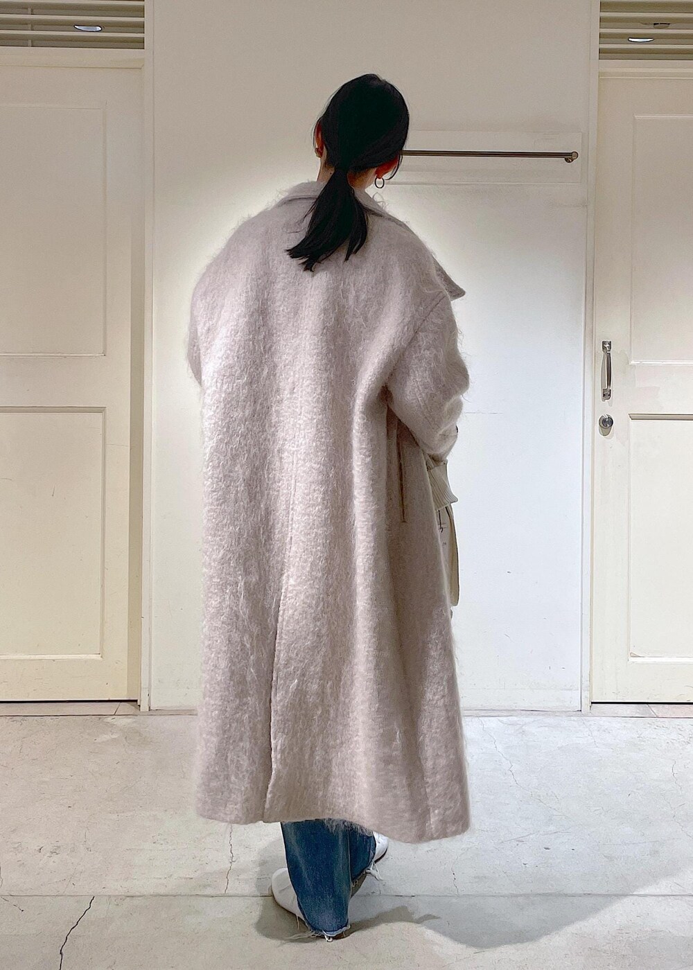 グレー系のその他アウター、ブルー系のデニムパンツ、ホワイト系のその他シューズを着用したレディースの冬コーディネートの7枚目の写真
