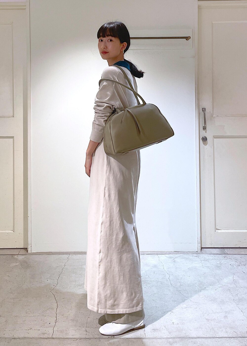 ホワイト系のその他シューズ、ベージュ系のスラックス、ホワイト系のチューブトップを着用したレディースの冬コーディネートの2枚目の写真