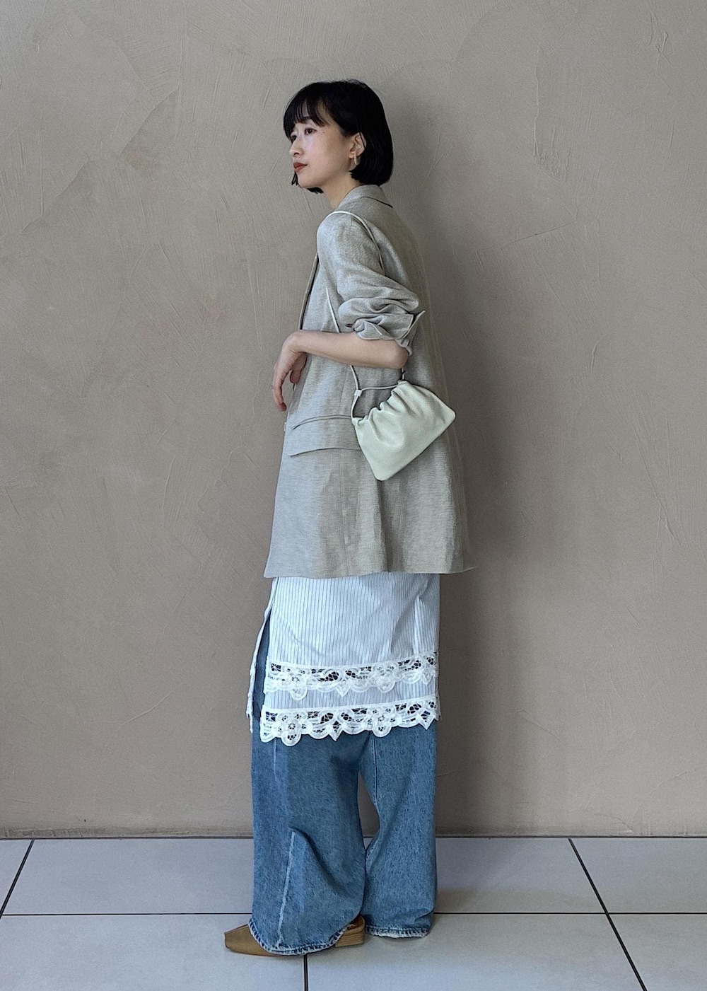 イエロー系のその他シューズ、ベージュ系のテーラードジャケット、ブルー系のデニムパンツを着用したレディースの冬コーディネートの5枚目の写真