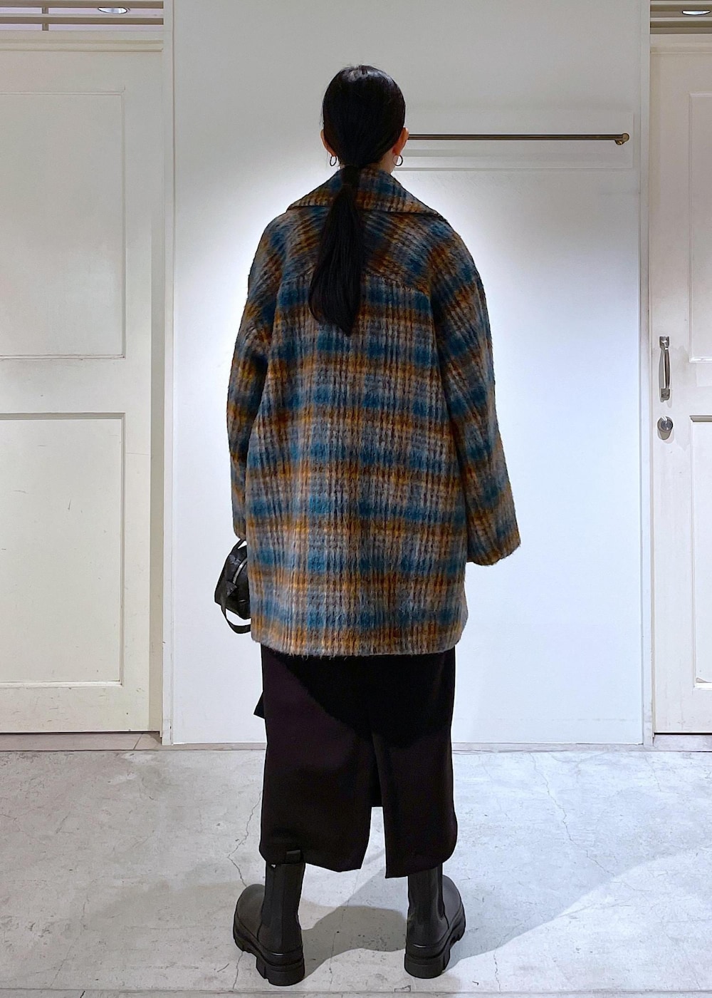 ブルー系のピーコート、ブラック系のブーツ、ブラック系のスカートを着用したレディースの秋コーディネートの3枚目の写真