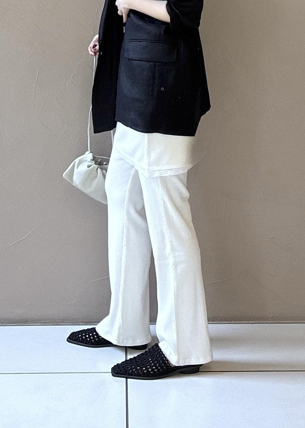 ブラック系のテーラードジャケット、ブラック系のサンダル、ホワイト系のキャミソールを着用したレディースの春コーディネートの4枚目の写真