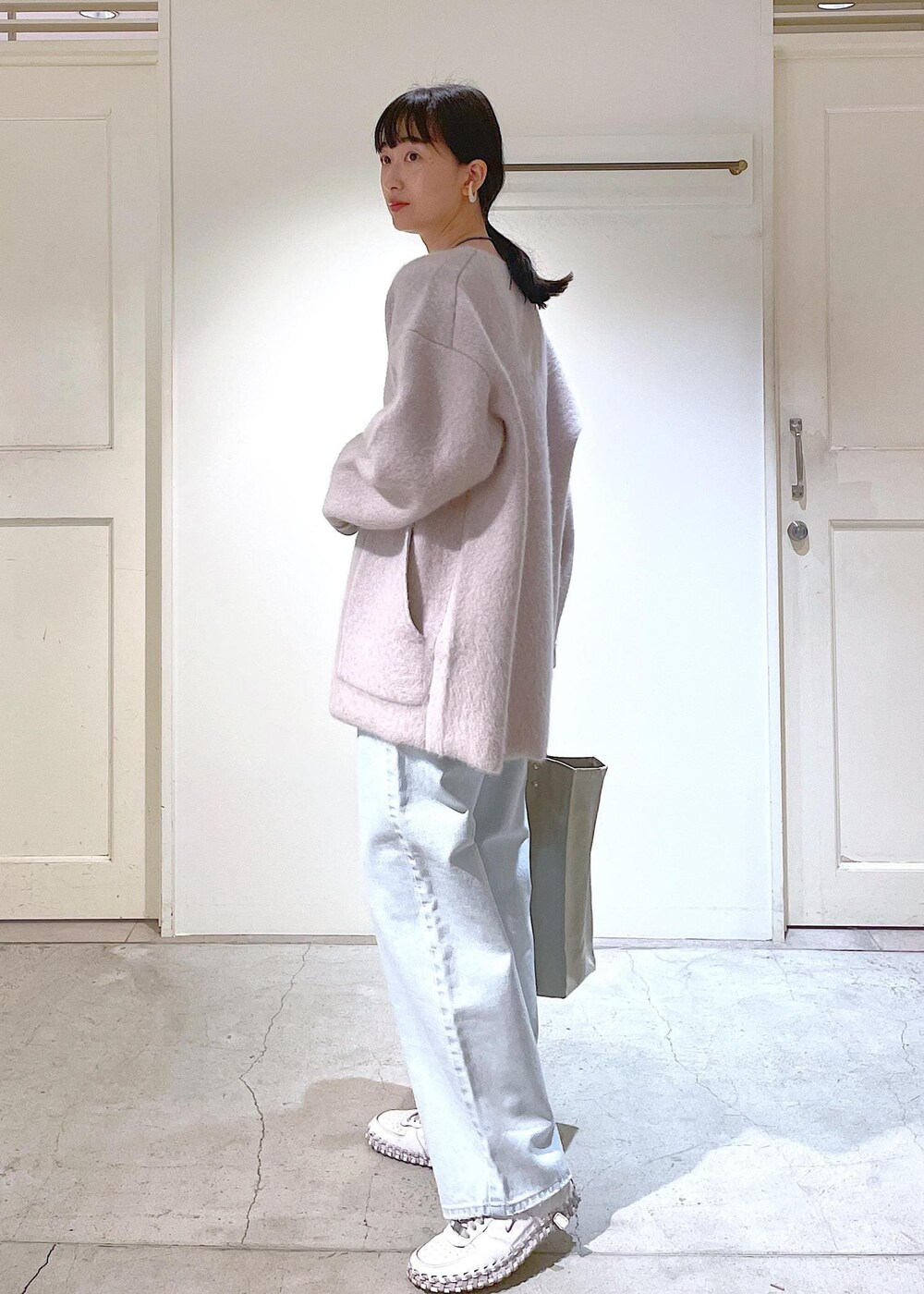 グレー系のトートバッグ、ホワイト系のチューブトップ、グレー系のブルゾンを着用したレディースの冬コーディネートの3枚目の写真