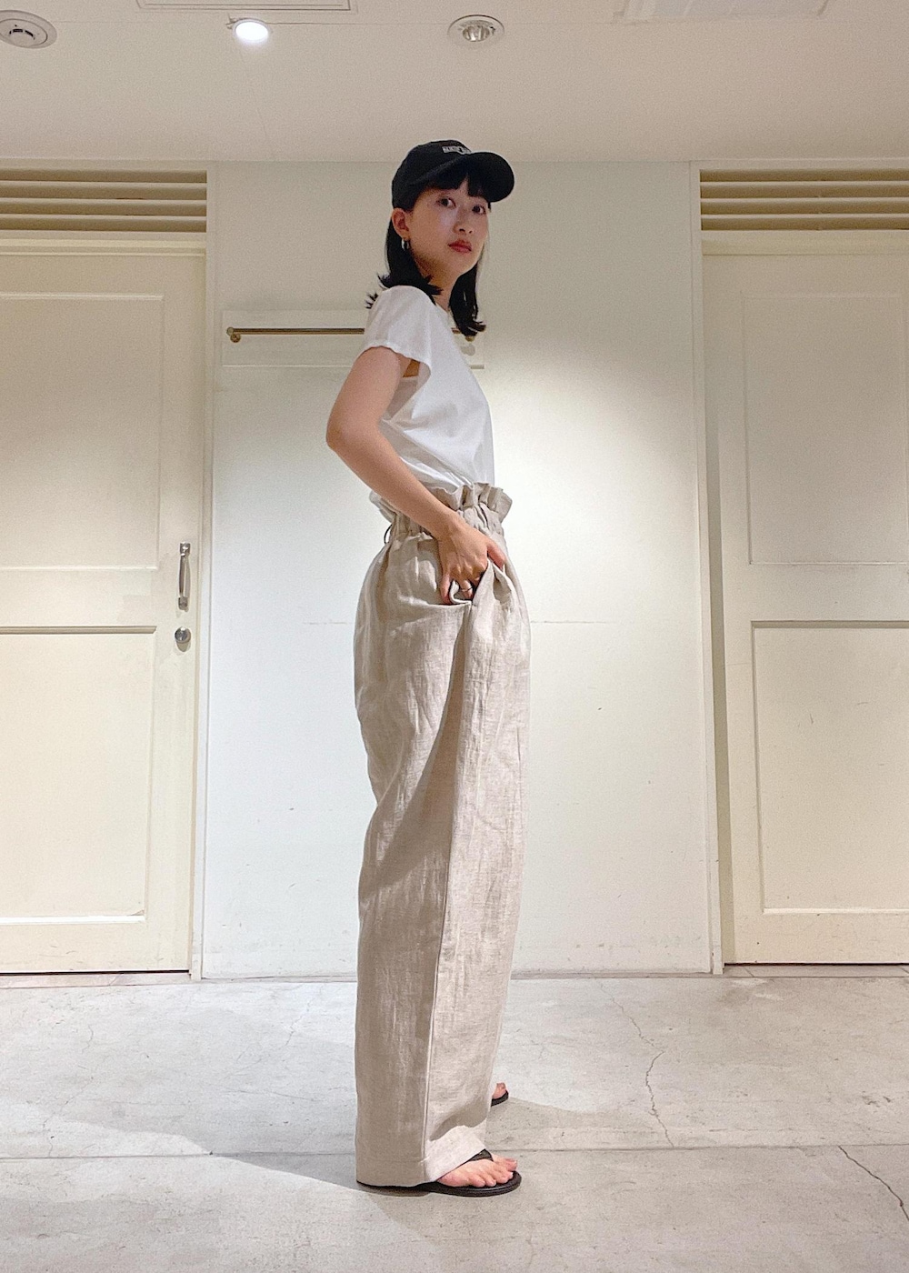 ブラック系のサンダル、グレー系のスラックス、ホワイト系のTシャツ/カットソーを着用したレディースの春コーディネートの6枚目の写真