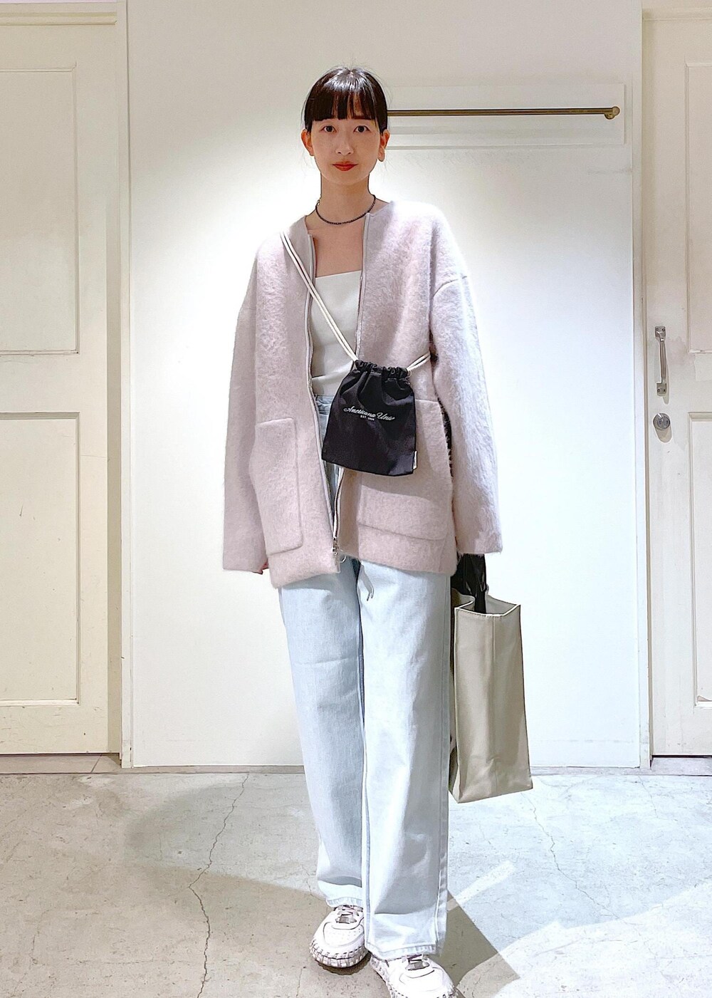 グレー系のトートバッグ、ホワイト系のチューブトップ、グレー系のブルゾンを着用したレディースの冬コーディネートの4枚目の写真