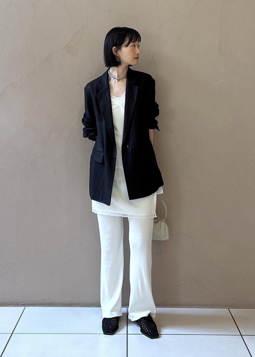 ブラック系のテーラードジャケット、ブラック系のサンダル、ホワイト系のキャミソールを着用したレディースの春コーディネートの9枚目の写真