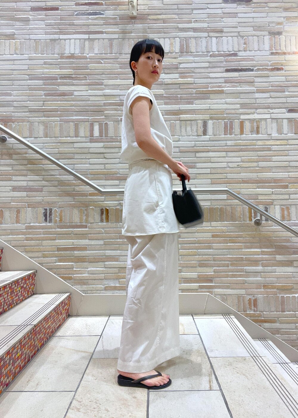 ホワイト系のTシャツ/カットソー、ホワイト系のその他パンツ、ブラック系のサンダルを着用したレディースの春コーディネートの3枚目の写真