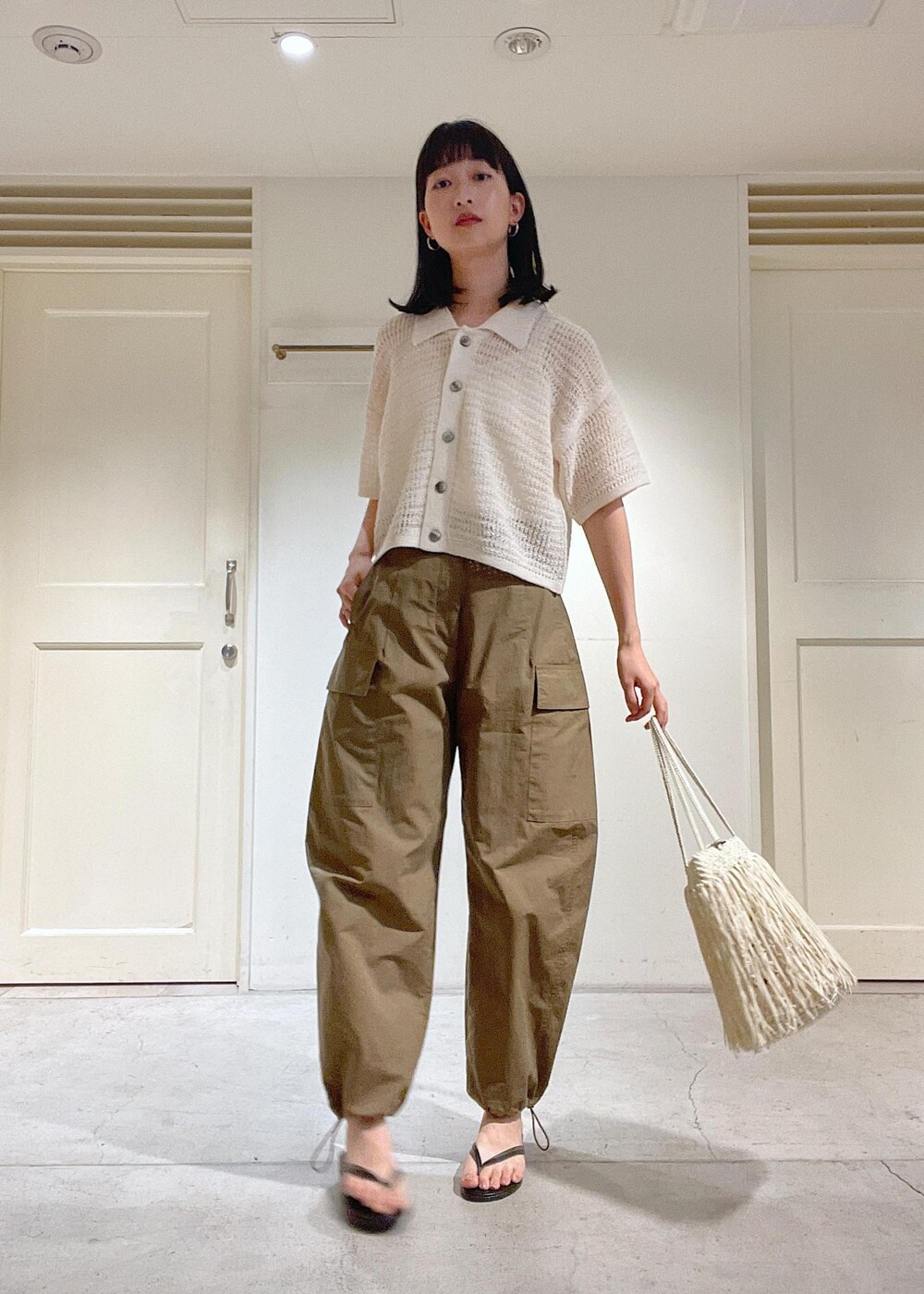 グリーン系のカーゴパンツ、ブラック系のサンダル、ホワイト系のトートバッグを着用したレディースの夏コーディネートの4枚目の写真