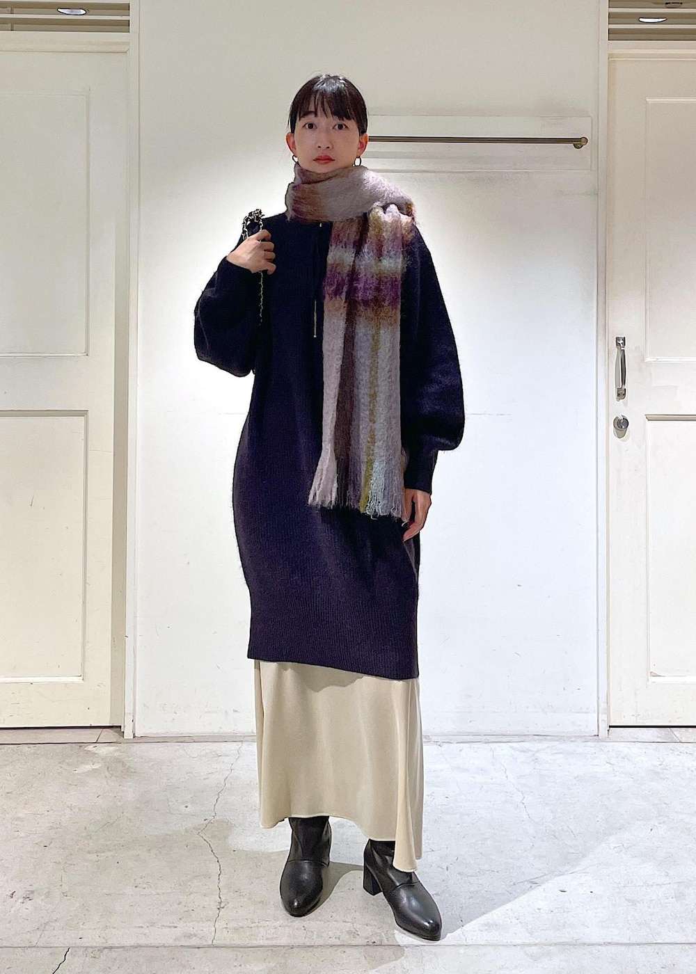 ブラック系のショルダーバッグ、ベージュ系のスカート、レッド系のワンピースを着用したレディースの秋コーディネートの4枚目の写真