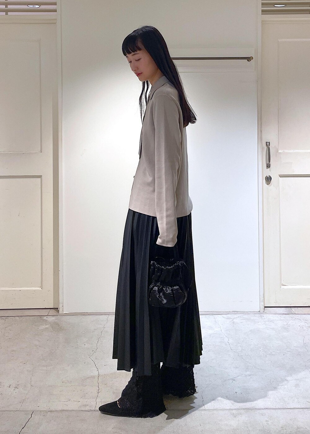 グレー系のカーディガン/ボレロ、ブラック系のスカート、ブラック系のショルダーバッグを着用したレディースの秋コーディネートの2枚目の写真