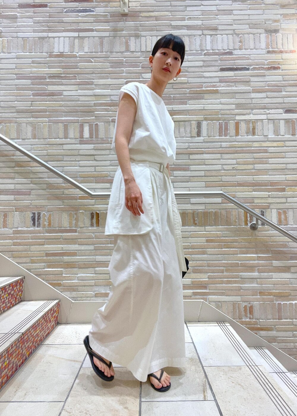 ホワイト系のTシャツ/カットソー、ホワイト系のその他パンツ、ブラック系のサンダルを着用したレディースの春コーディネートの2枚目の写真