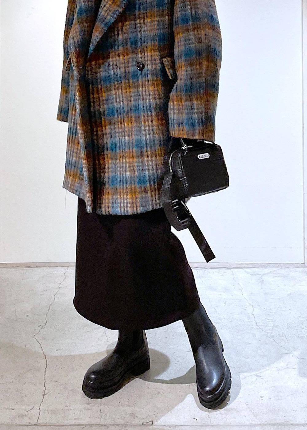 ブルー系のピーコート、ブラック系のブーツ、ブラック系のスカートを着用したレディースの秋コーディネートの4枚目の写真