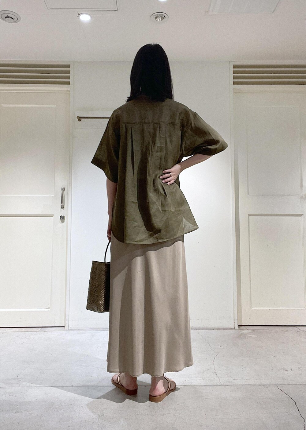 ブラウン系のサンダル、ベージュ系のスカート、ゴールド系のかごバッグを着用したレディースの春コーディネートの3枚目の写真