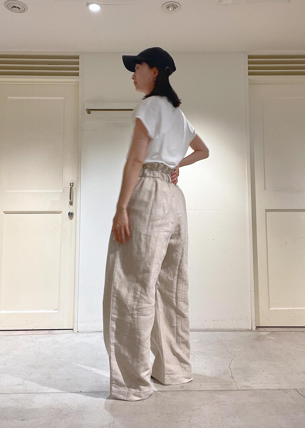 ブラック系のサンダル、グレー系のスラックス、ホワイト系のTシャツ/カットソーを着用したレディースの春コーディネートの5枚目の写真