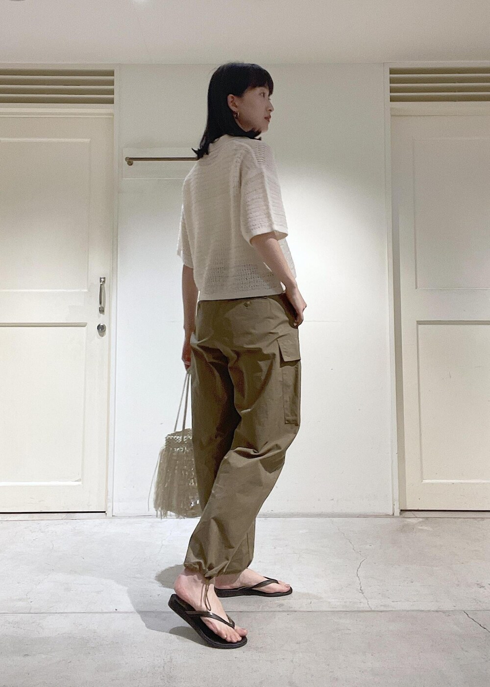 グリーン系のカーゴパンツ、ブラック系のサンダル、ホワイト系のトートバッグを着用したレディースの夏コーディネートの3枚目の写真