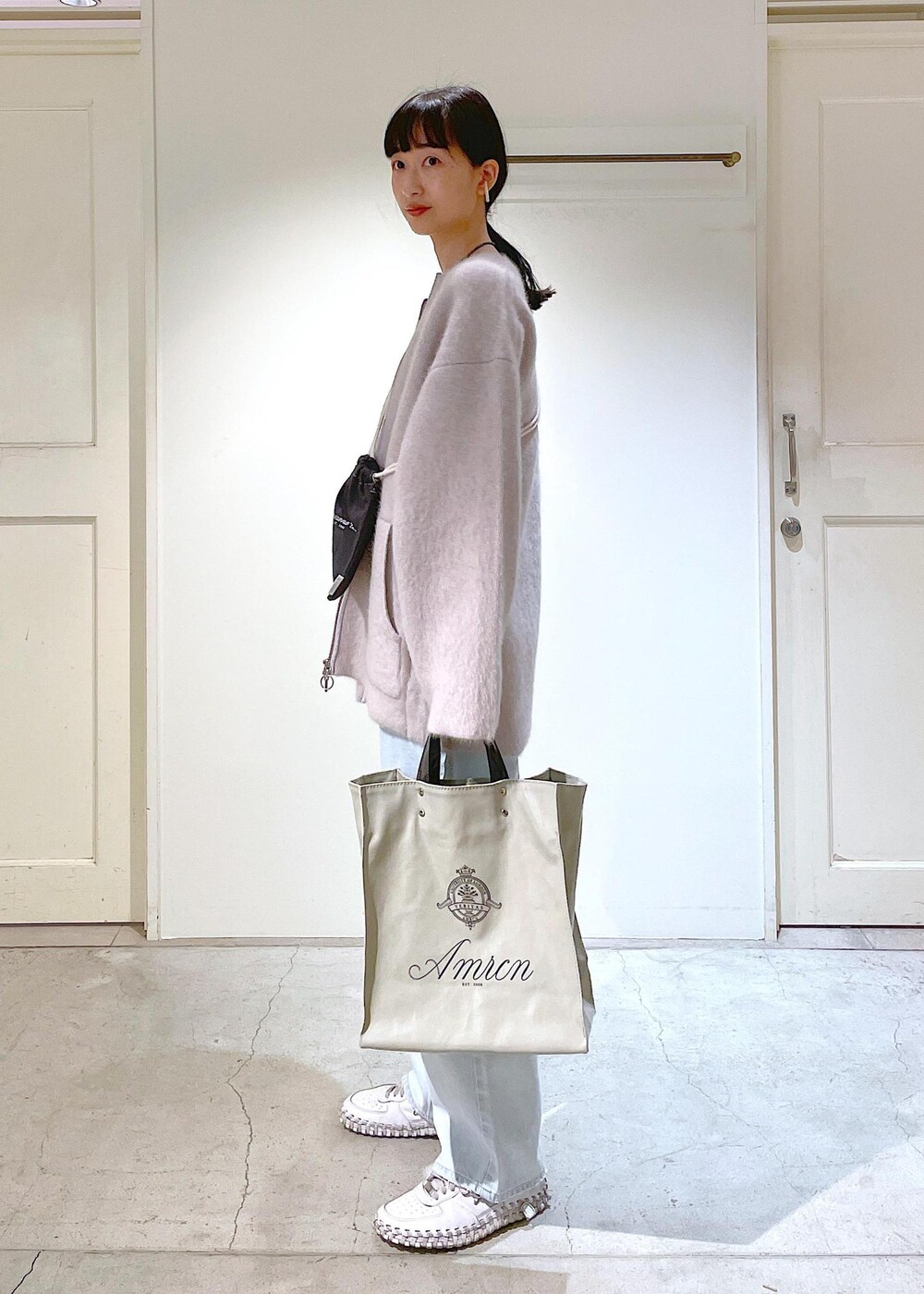 グレー系のトートバッグ、ホワイト系のチューブトップ、グレー系のブルゾンを着用したレディースの冬コーディネートの2枚目の写真