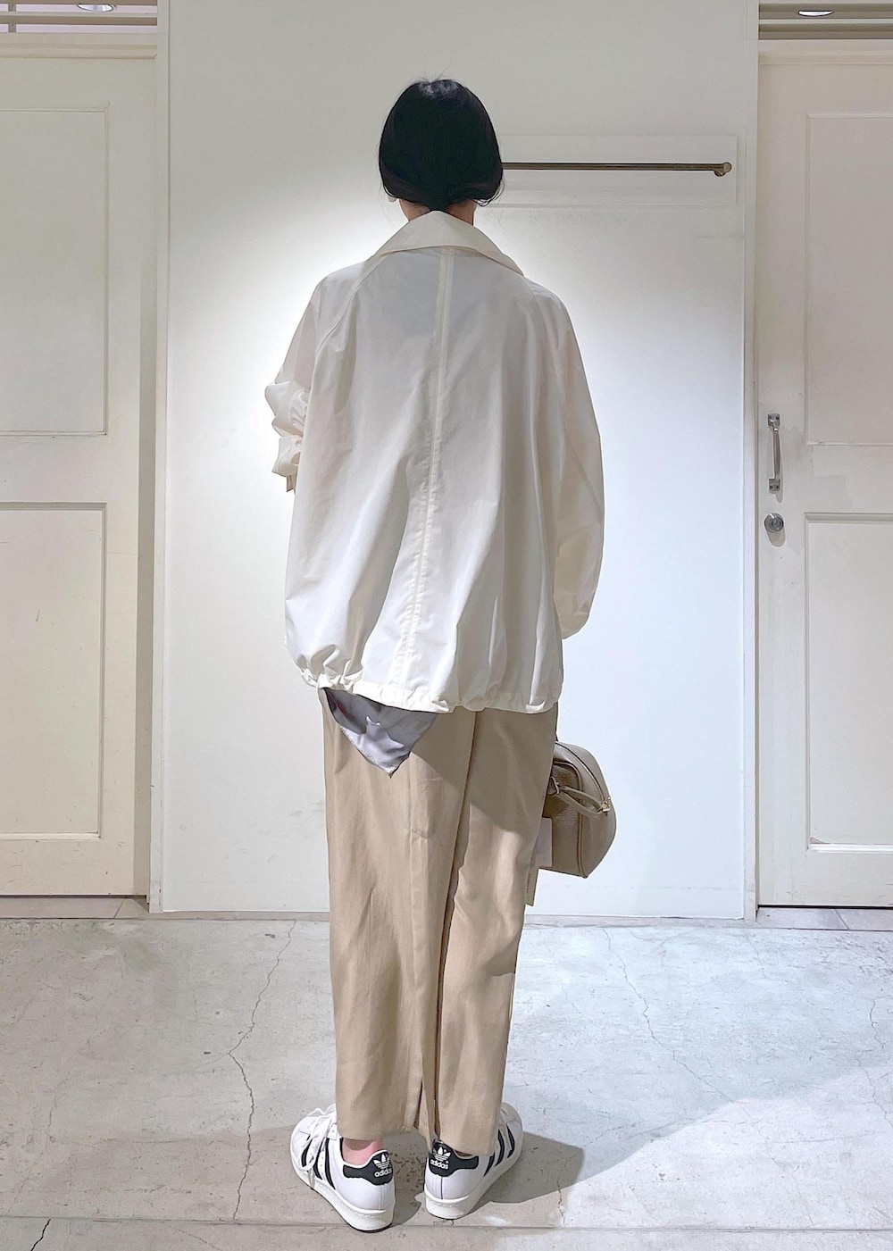 ベージュ系のワンピース、ホワイト系のブルゾン、ホワイト系のスニーカーを着用したレディースの冬コーディネートの7枚目の写真