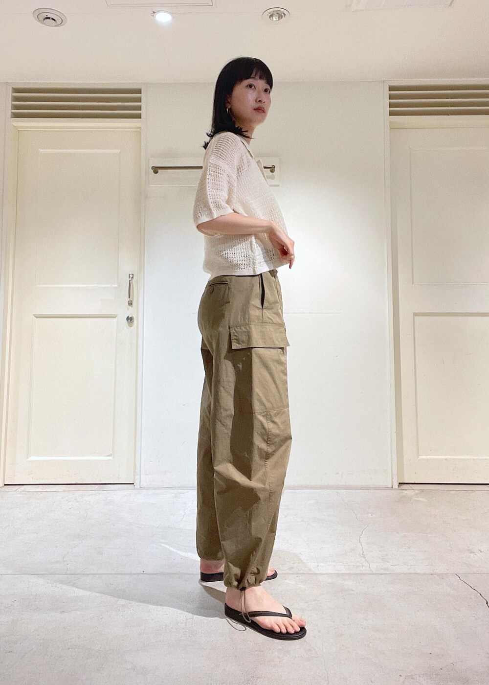 グリーン系のカーゴパンツ、ブラック系のサンダル、ホワイト系のトートバッグを着用したレディースの夏コーディネートの2枚目の写真