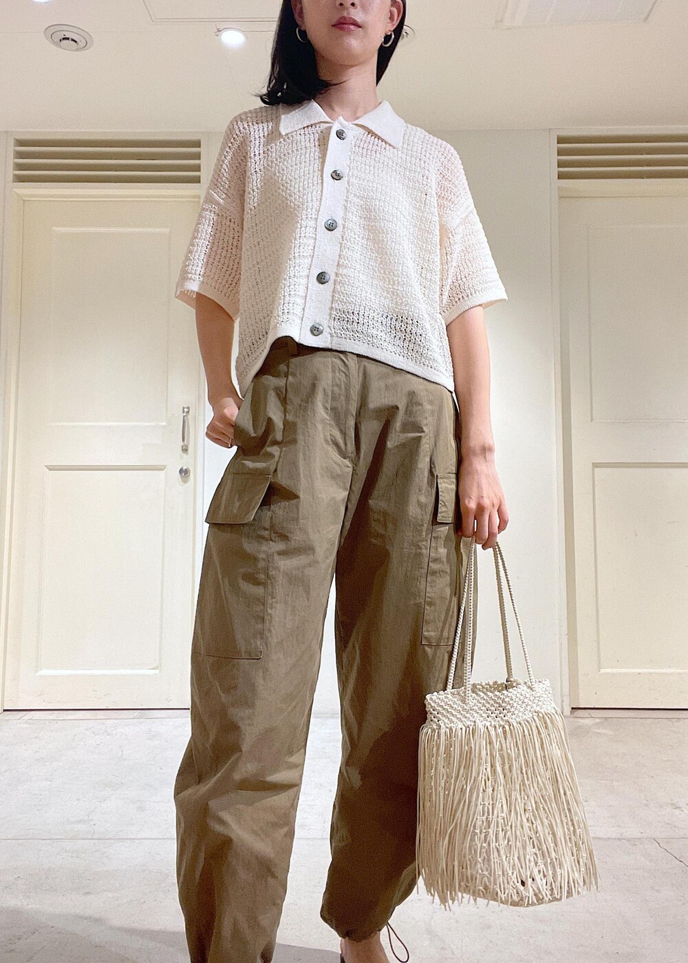 グリーン系のカーゴパンツ、ブラック系のサンダル、ホワイト系のトートバッグを着用したレディースの夏コーディネートの5枚目の写真