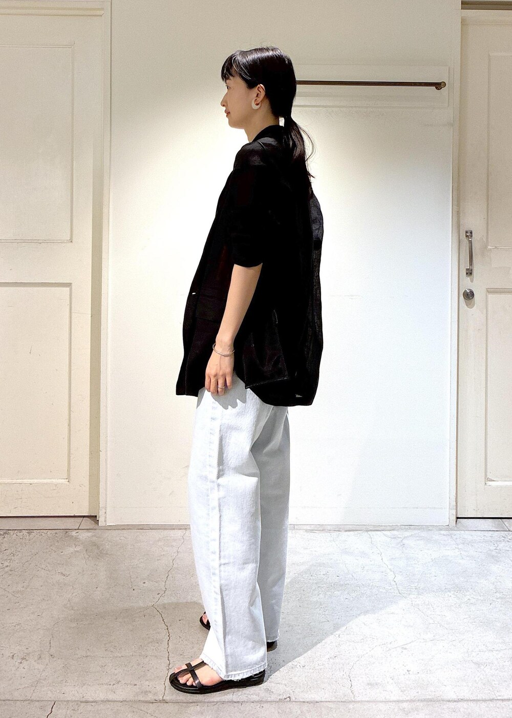 ブルー系のデニムパンツ、ブラック系のサンダル、グレー系のテーラードジャケットを着用したレディースの夏コーディネートの2枚目の写真