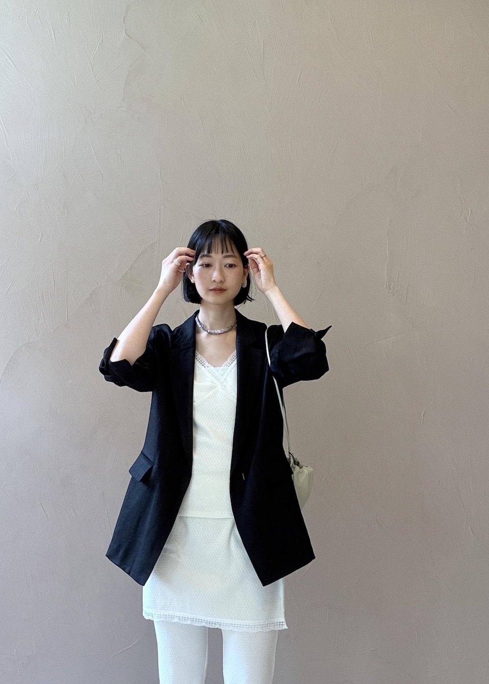 ブラック系のテーラードジャケット、ブラック系のサンダル、ホワイト系のキャミソールを着用したレディースの春コーディネートの6枚目の写真