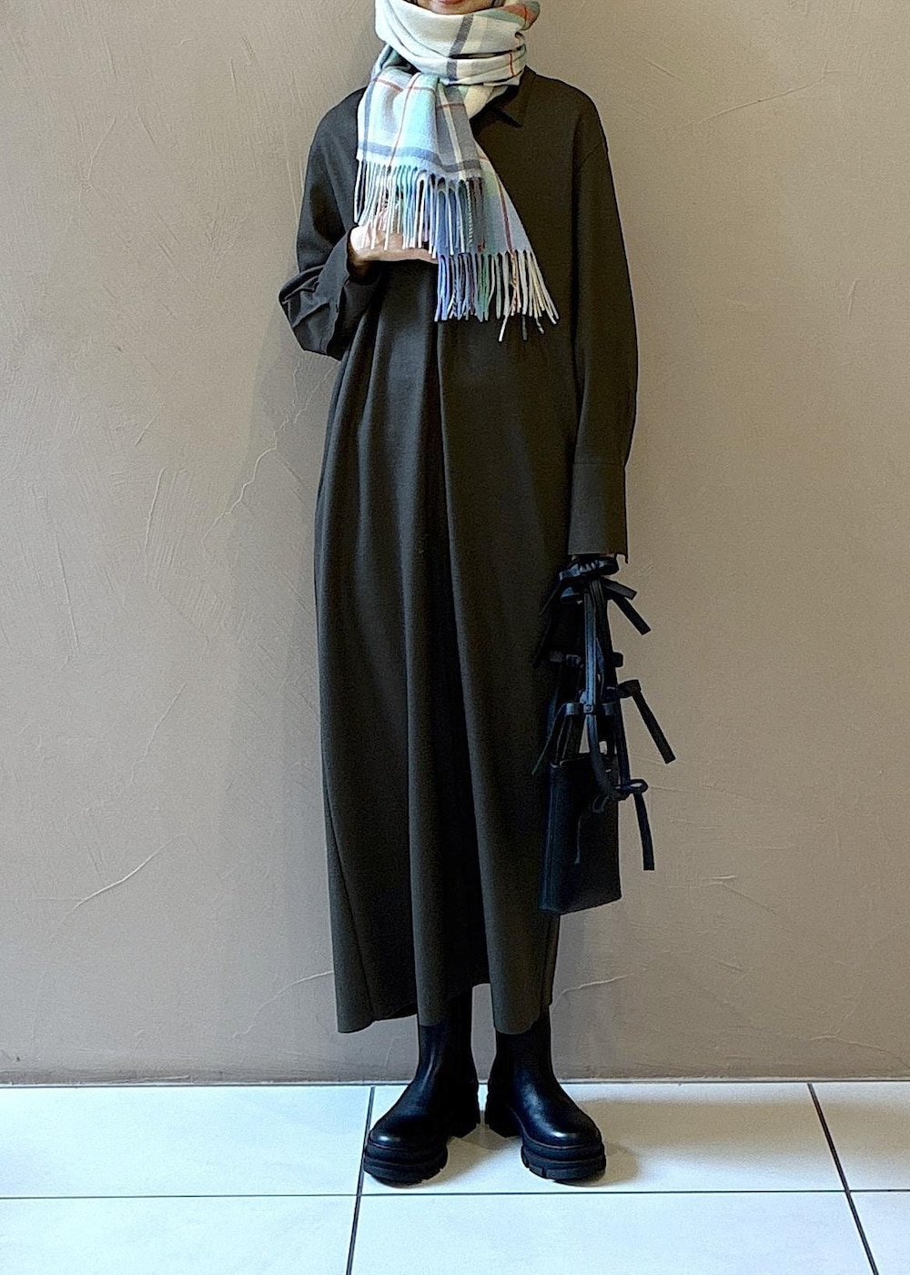 ブラック系のブーツ、グリーン系のワンピース、ホワイト系のニット/セーターを着用したレディースの冬コーディネートの3枚目の写真