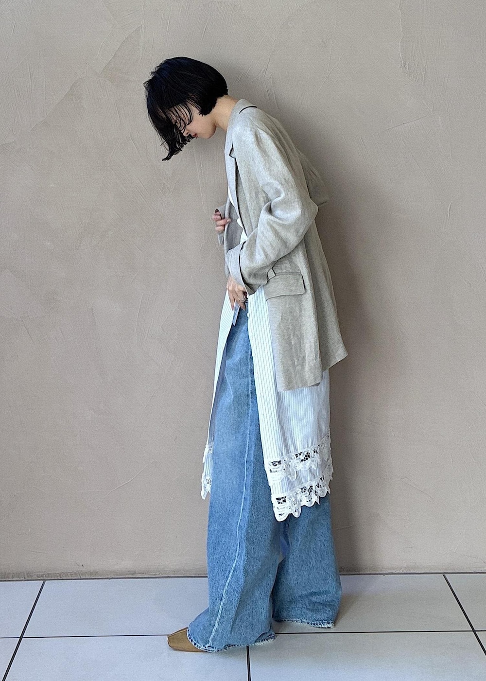 イエロー系のその他シューズ、ベージュ系のテーラードジャケット、ブルー系のデニムパンツを着用したレディースの冬コーディネートの2枚目の写真