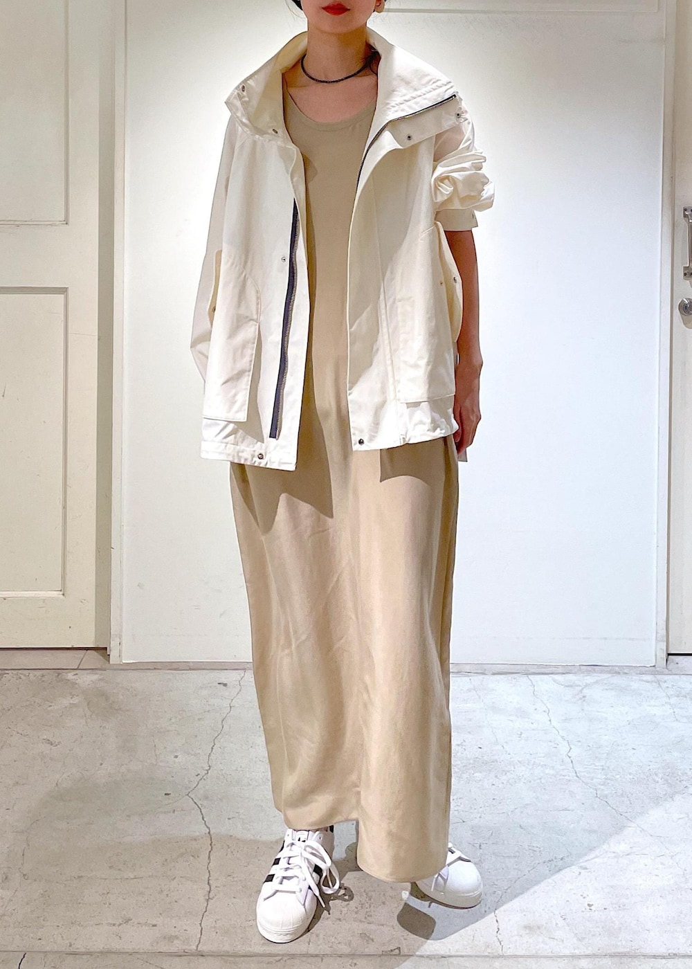 ベージュ系のワンピース、ホワイト系のブルゾン、ホワイト系のスニーカーを着用したレディースの冬コーディネートの4枚目の写真