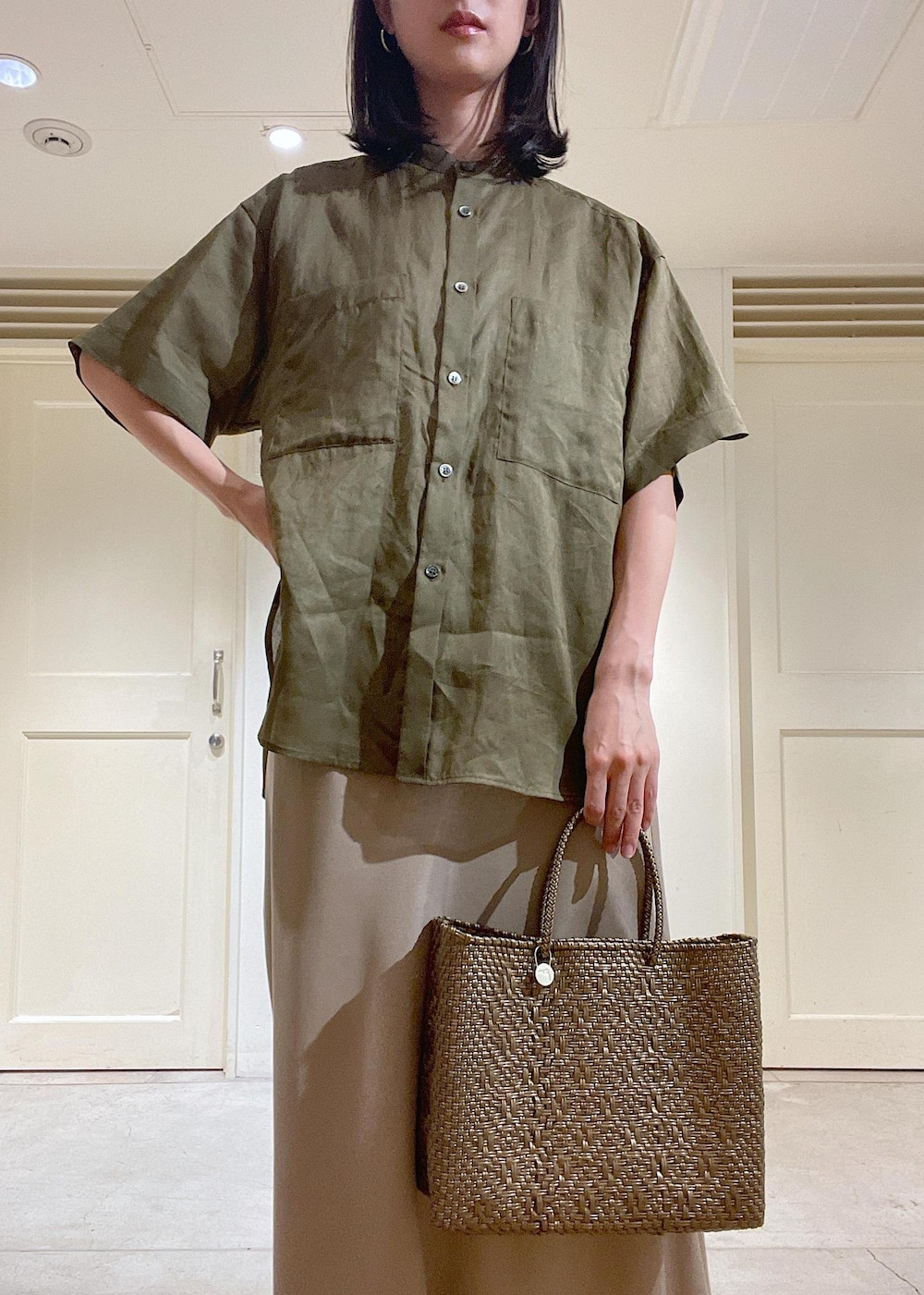 ブラウン系のサンダル、ベージュ系のスカート、ゴールド系のかごバッグを着用したレディースの春コーディネートの5枚目の写真