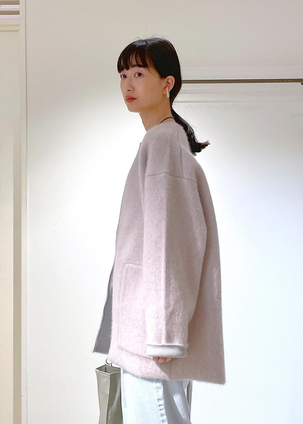 グレー系のトートバッグ、ホワイト系のチューブトップ、グレー系のブルゾンを着用したレディースの冬コーディネートの7枚目の写真