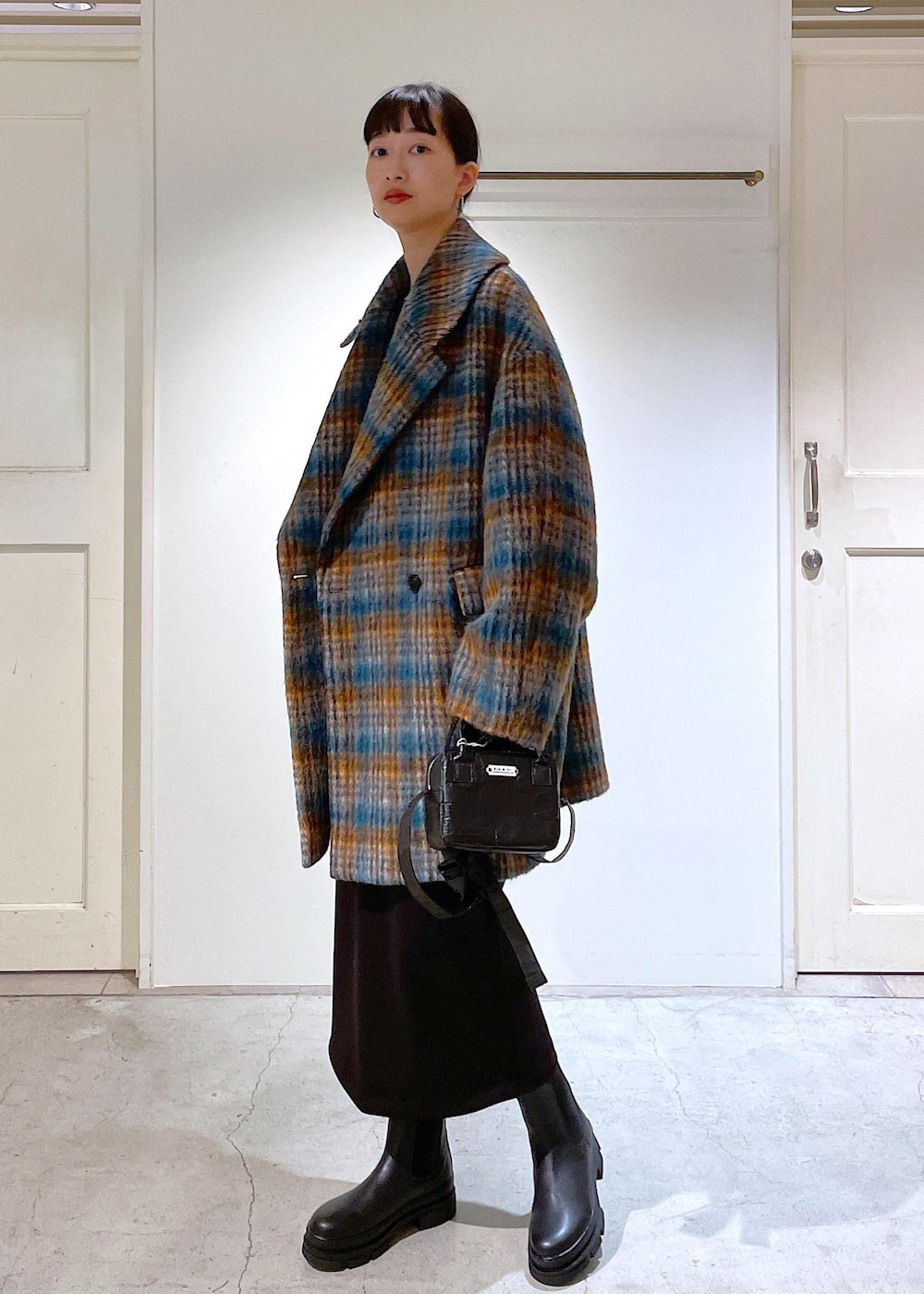 ブルー系のピーコート、ブラック系のブーツ、ブラック系のスカートを着用したレディースの秋コーディネートの2枚目の写真