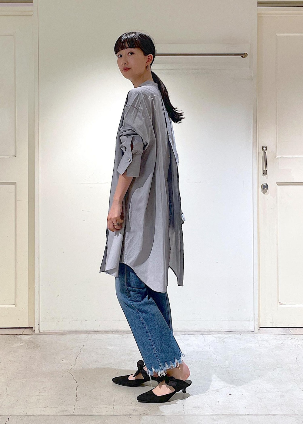 ブルー系のデニムパンツ、グレー系のシャツ/ブラウス、ホワイト系のトートバッグを着用したレディースの夏コーディネートの3枚目の写真