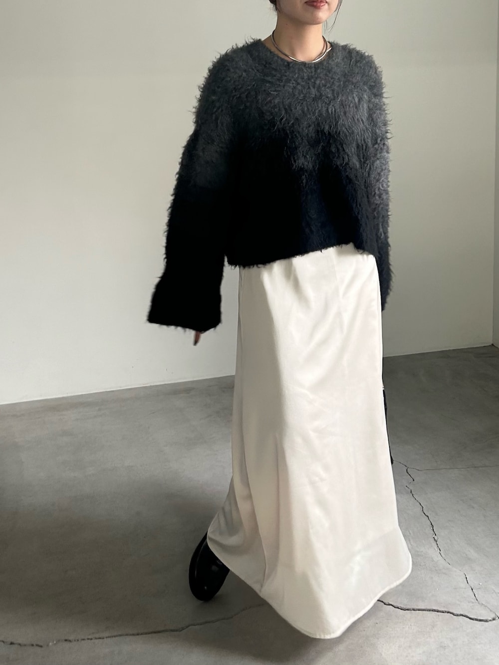 ブラック系のニット/セーター、ブラック系のハンドバッグ、ホワイト系のスカートを着用したレディースの秋コーディネートの4枚目の写真