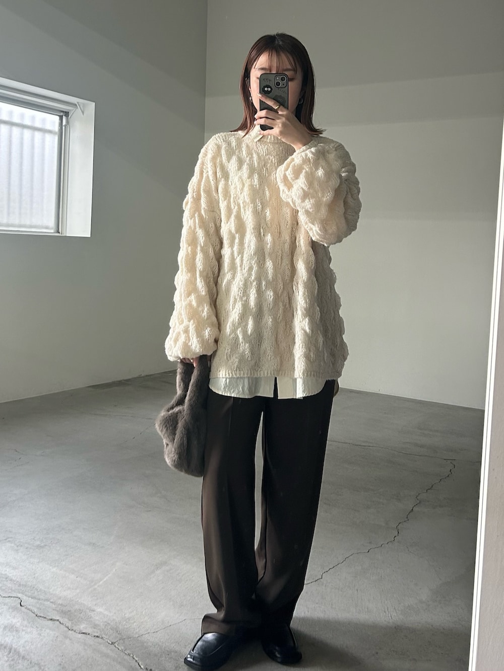 ホワイト系のニット/セーター、ホワイト系のシャツ/ブラウス、グレー系のハンドバッグを着用したレディースの冬コーディネートの7枚目の写真