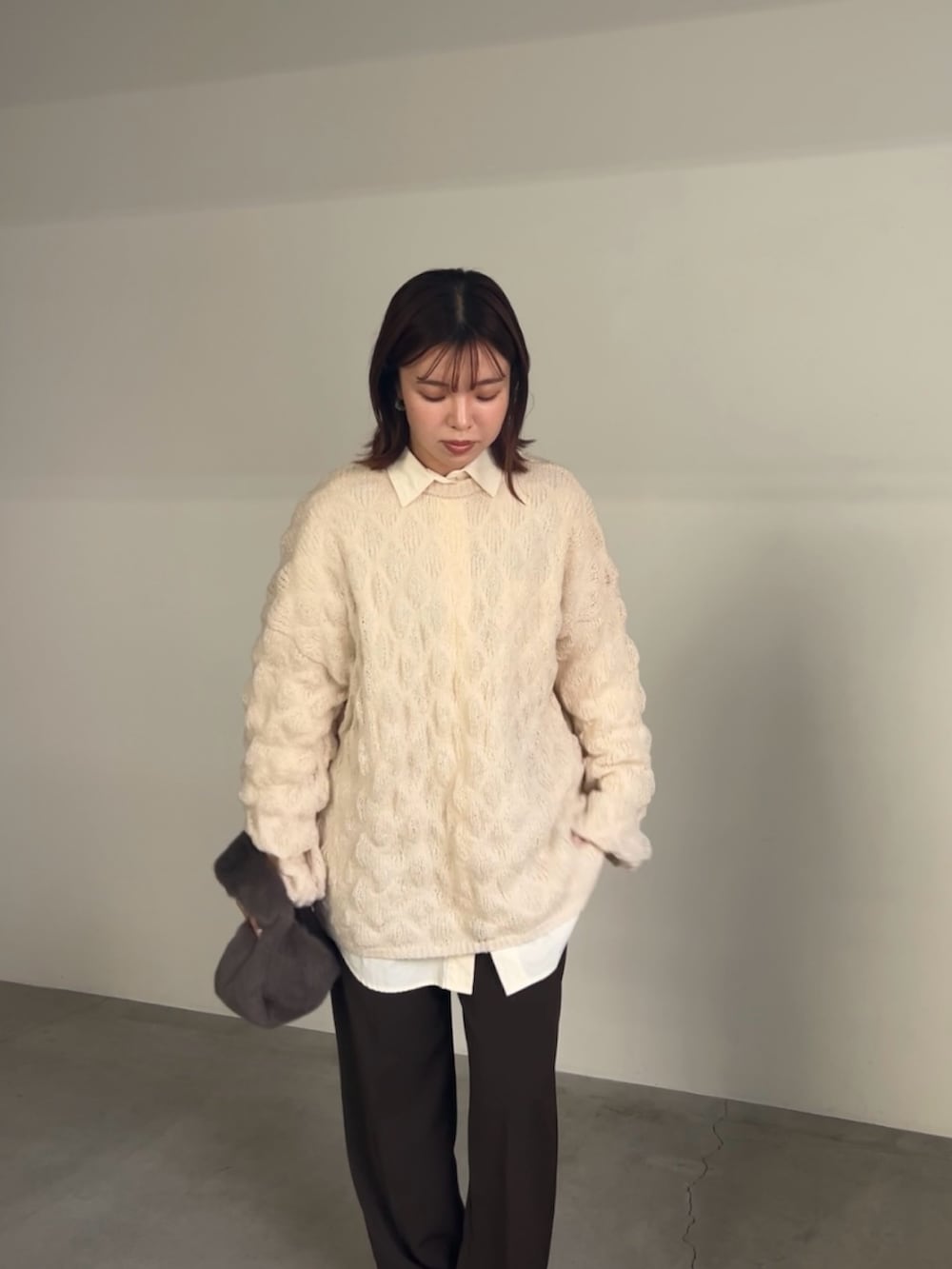 ホワイト系のニット/セーター、ホワイト系のシャツ/ブラウス、グレー系のハンドバッグを着用したレディースの冬コーディネートの6枚目の写真