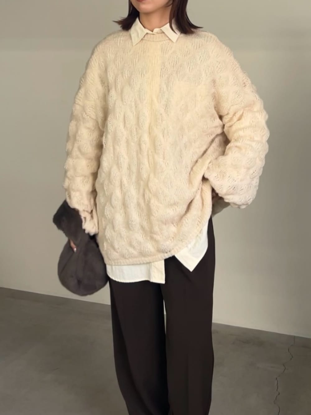 ホワイト系のニット/セーター、ホワイト系のシャツ/ブラウス、グレー系のハンドバッグを着用したレディースの冬コーディネートの3枚目の写真