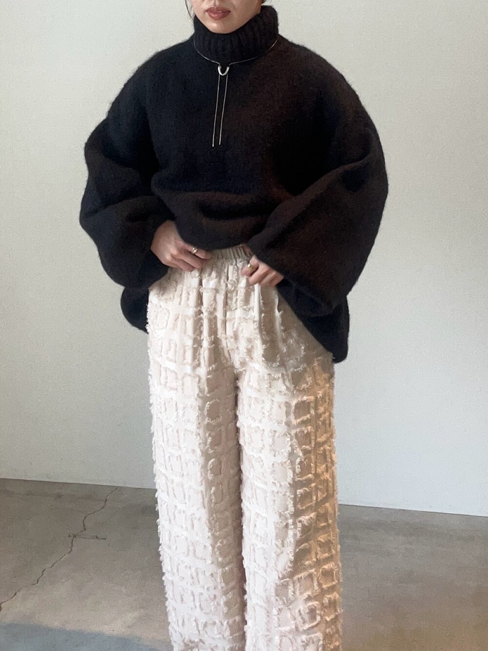 ブラック系のニット/セーター、ホワイト系のその他パンツ、シルバー系のネックレスを着用したレディースの秋コーディネートの6枚目の写真