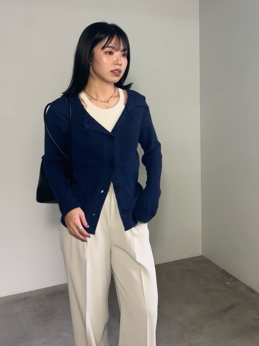 ブルー系のカーディガン/ボレロ、ホワイト系のスラックス、ブラック系のショルダーバッグを着用したレディースの冬コーディネートの3枚目の写真