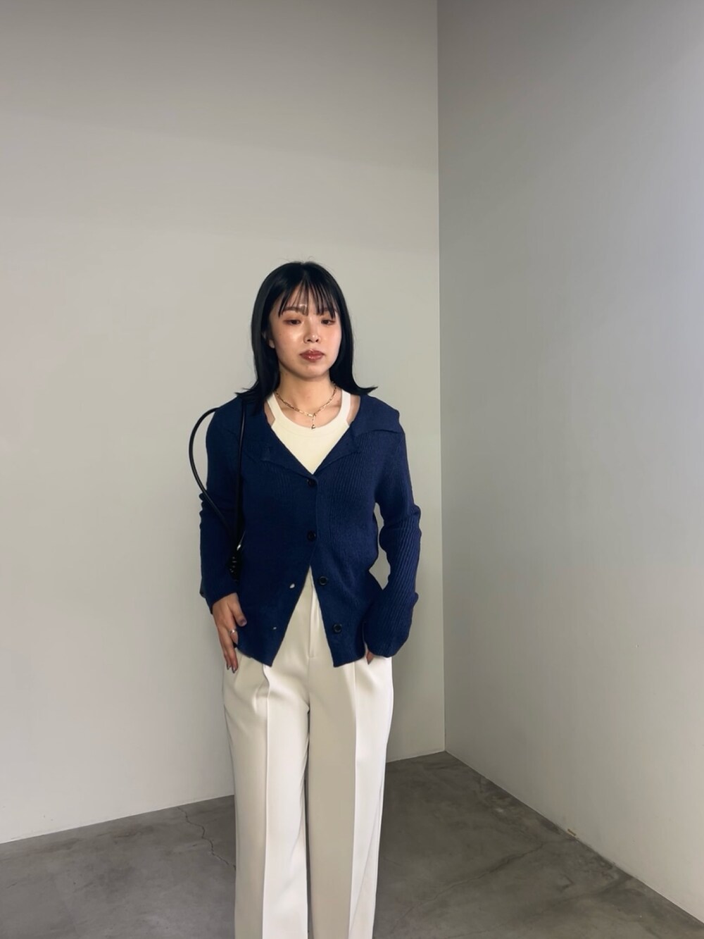 ブルー系のカーディガン/ボレロ、ホワイト系のスラックス、ブラック系のショルダーバッグを着用したレディースの冬コーディネートの2枚目の写真