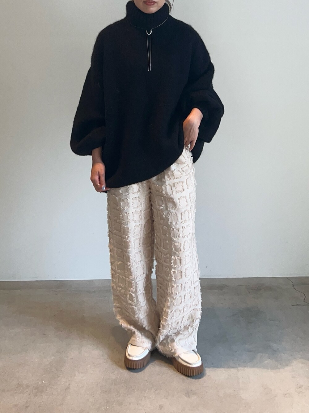 ブラック系のニット/セーター、ホワイト系のその他パンツ、シルバー系のネックレスを着用したレディースの秋コーディネートの7枚目の写真