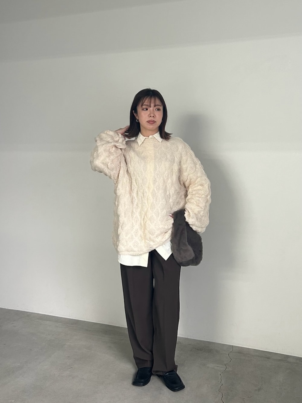 ホワイト系のニット/セーター、ホワイト系のシャツ/ブラウス、グレー系のハンドバッグを着用したレディースの冬コーディネートの4枚目の写真