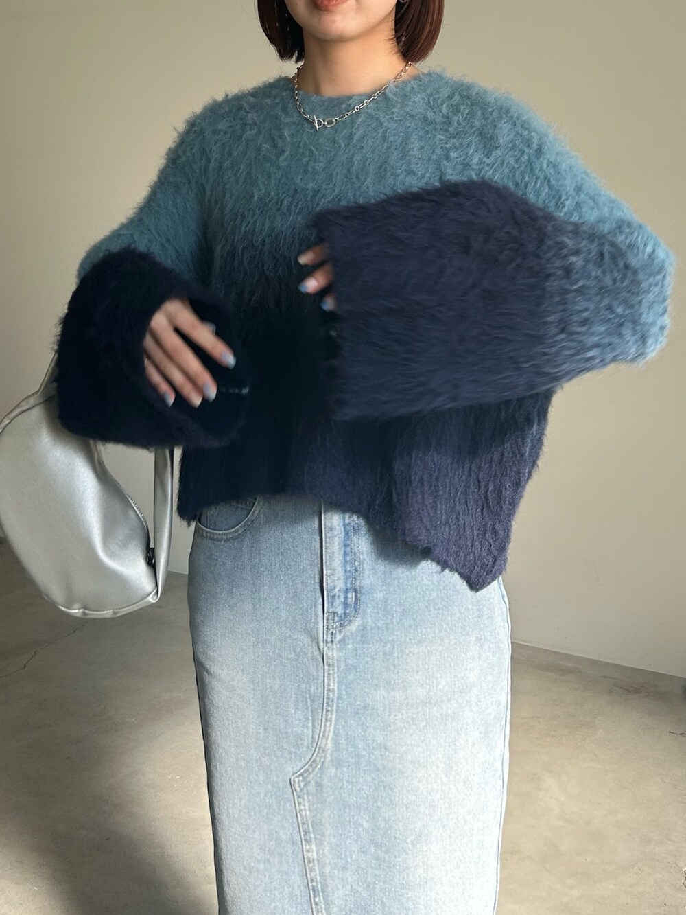 ブルー系のニット/セーター、ブルー系のデニムスカート、シルバー系のショルダーバッグを着用したレディースの夏コーディネートの5枚目の写真