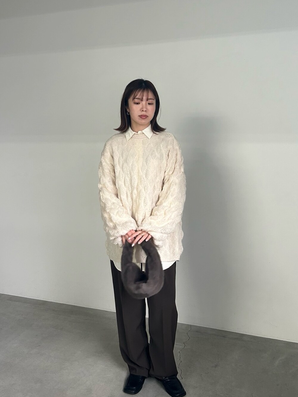 ホワイト系のニット/セーター、ホワイト系のシャツ/ブラウス、グレー系のハンドバッグを着用したレディースの冬コーディネートの5枚目の写真