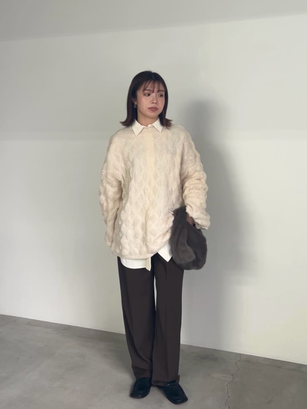 ホワイト系のニット/セーター、ホワイト系のシャツ/ブラウス、グレー系のハンドバッグを着用したレディースの冬コーディネートの2枚目の写真