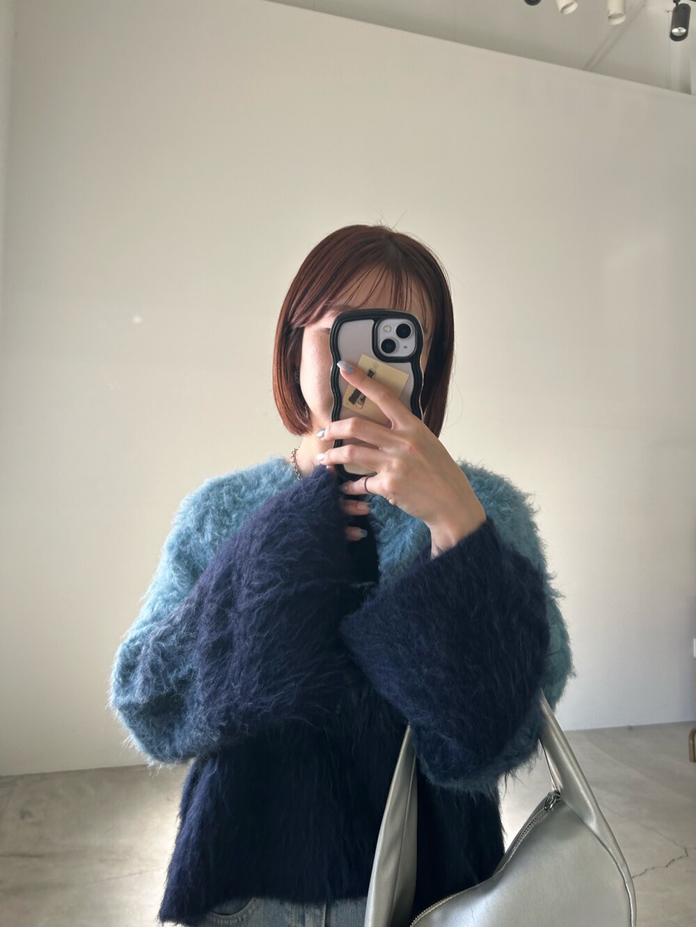 ブルー系のニット/セーター、ブルー系のデニムスカート、シルバー系のショルダーバッグを着用したレディースの夏コーディネートの6枚目の写真