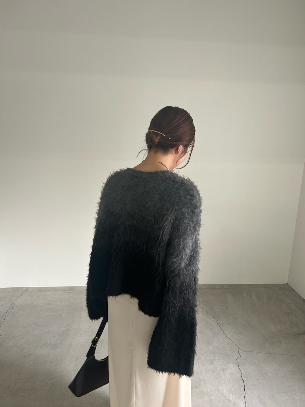 ブラック系のニット/セーター、ブラック系のハンドバッグ、ホワイト系のスカートを着用したレディースの秋コーディネートの5枚目の写真