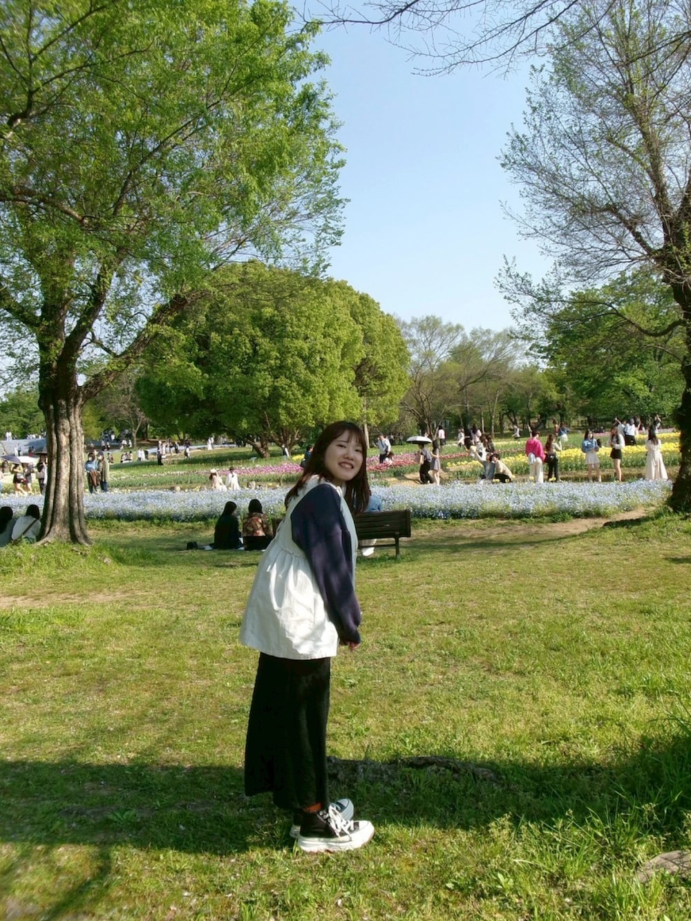 ブラック系のスカート、ホワイト系のベスト、ブルー系のスウェットを着用したレディースの春コーディネートの2枚目の写真