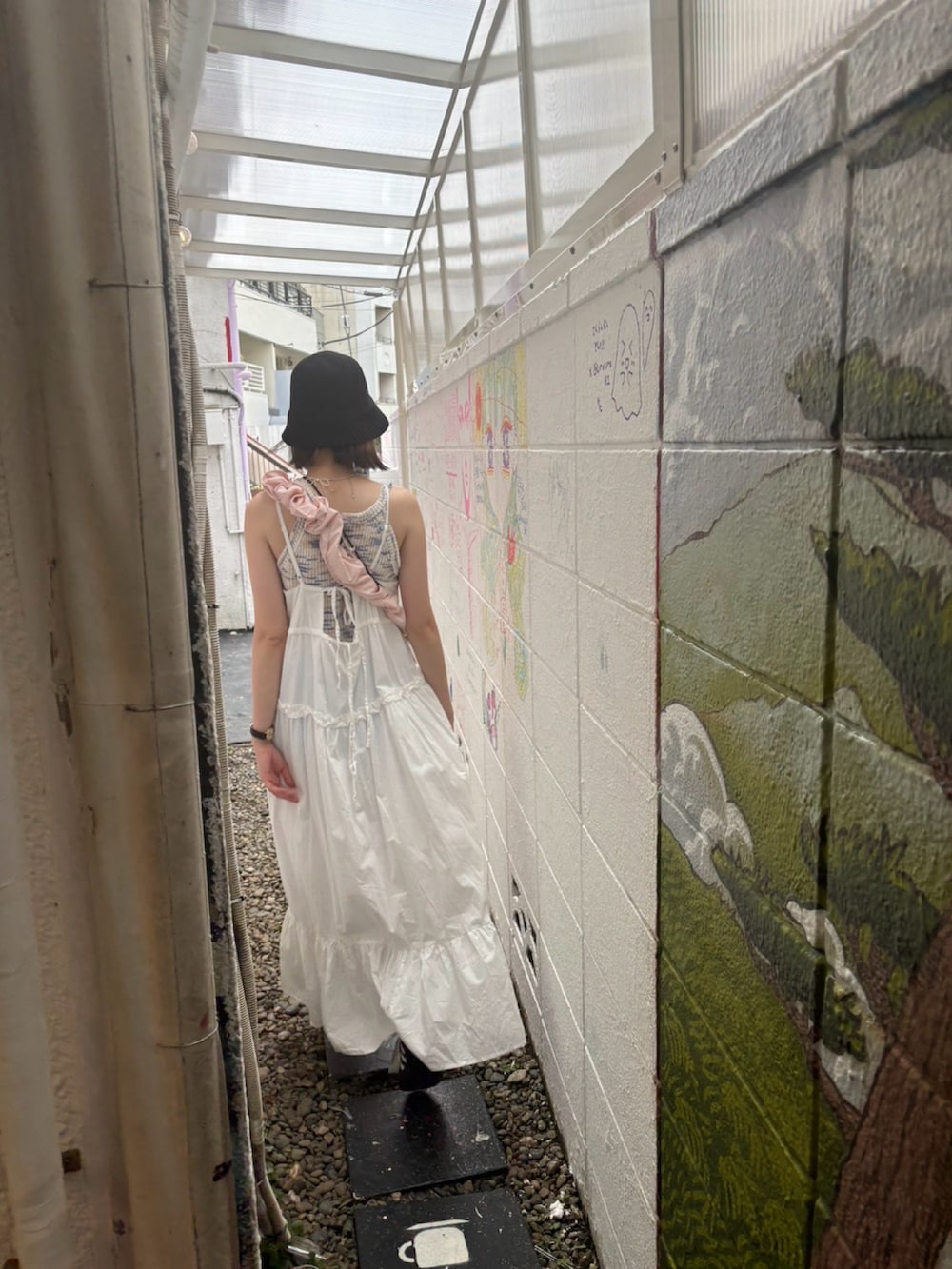 ピンク系のショルダーバッグ、ブラック系のスニーカー、ホワイト系のワンピースを着用したレディースの夏コーディネートの2枚目の写真